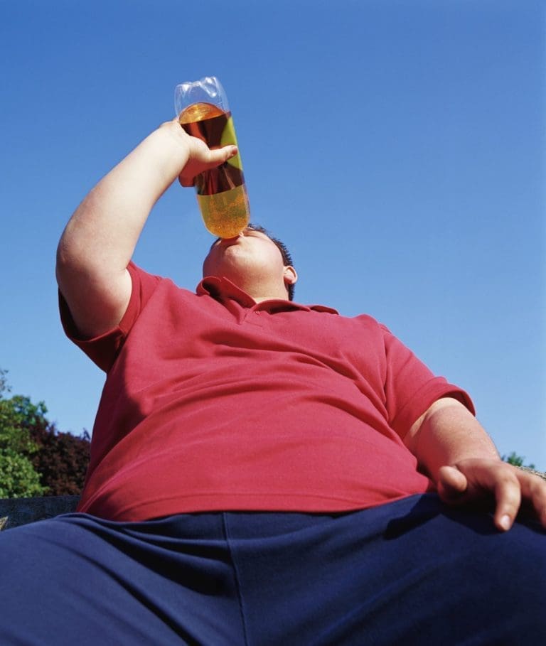 Overweight Teenage Man Drinking From a Bottle