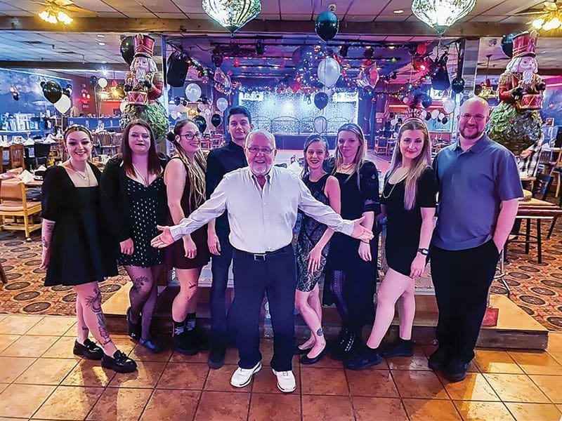 BANKING ON SUCESS Pictured center, Dennis Doughty—or "Mr. Doughty," as nearly everyone calls him—is the man behind the Banque's five decades in business. He was recently the guest of honor at an anniversary celebration.