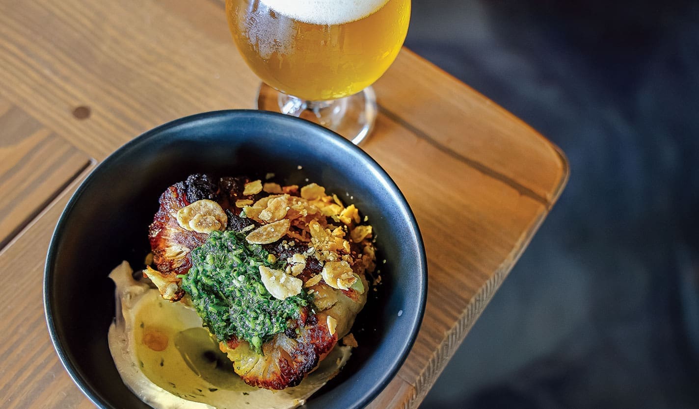 The Roasted Cauliflower Chimichurri with tahini yogurt, chimichurri sauce, crispy garlic and olive oil with a glass of beer at Pacifica