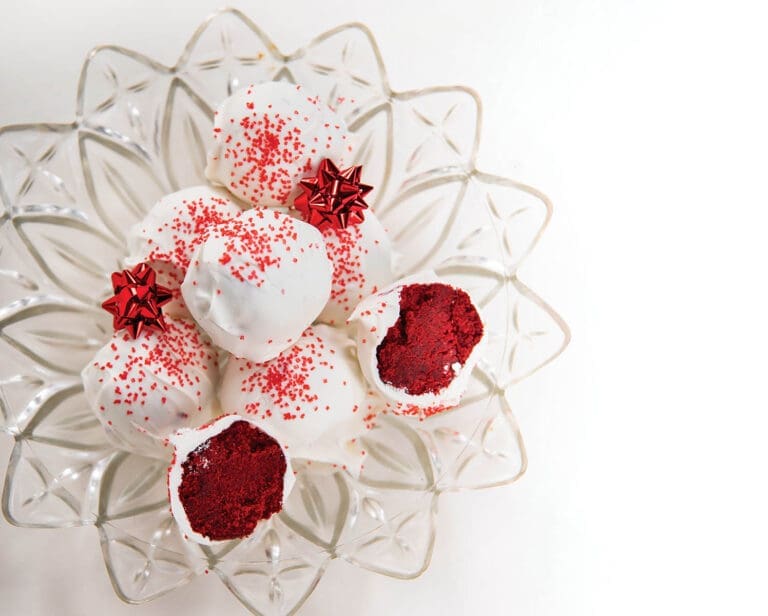 Red velvet cake balls coated in white chocolate with red sprinkles, arranged on a clear glass star-shaped plate, two cut open.