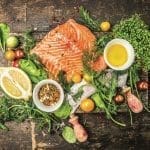 fresh salmon fillet with fresh healthy herbs,vegetables, oil and spices on rustic wooden background, top view
