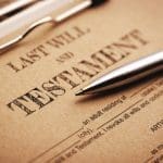 A close-up of a "Last Will and Testament" form on kraft paper, with a silver pen resting on the title.