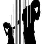 Black silhouette of an adult and a small child behind vertical bars, both with heads bowed and hands to their heads.