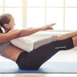 Beautiful young woman and charming little girl are smiling while doing yoga together in fitness hall