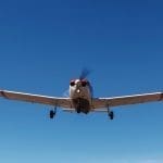 The plane Piper Cherokee low flies over the runway. A small private airfield with different planes. Private aviation