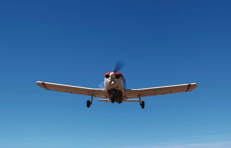 The plane Piper Cherokee low flies over the runway. A small private airfield with different planes. Private aviation