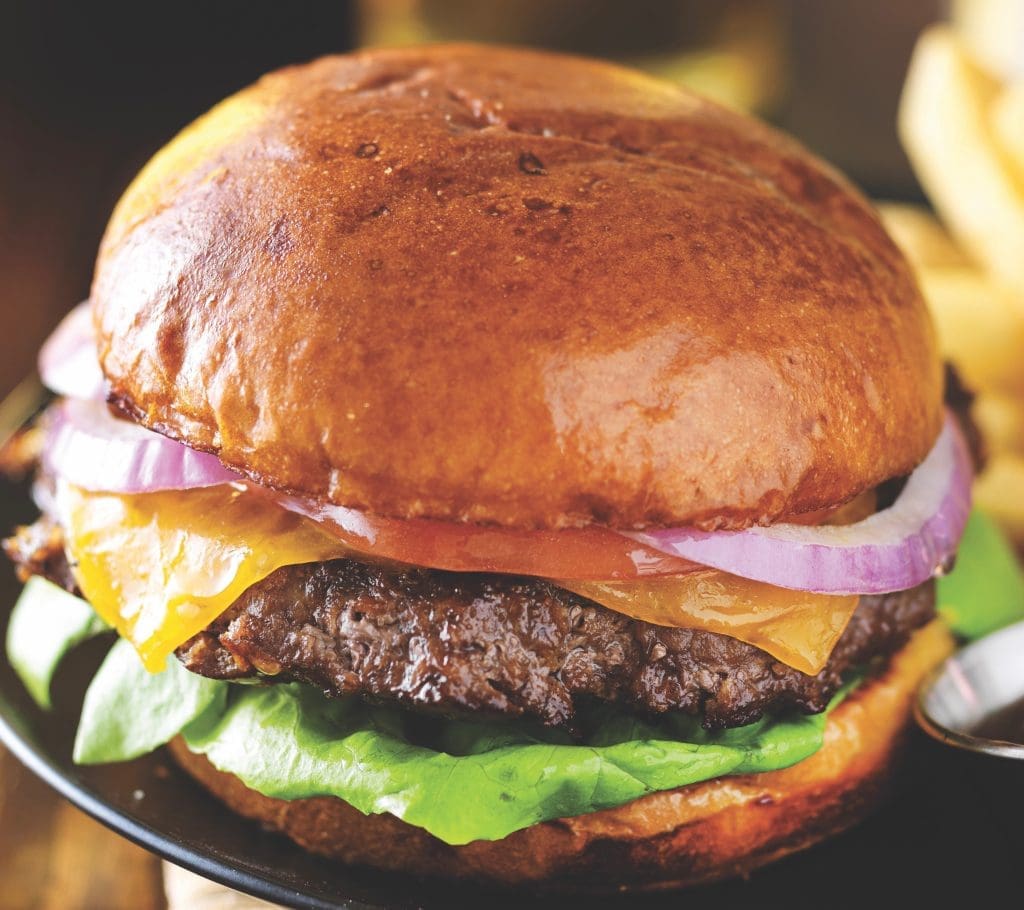 cheeseburger and fries on plate served with beer at restaurant