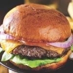 cheeseburger and fries on plate served with beer at restaurant