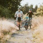A father and mother ride mountain bikes together with their two small children. A fun way to spend time together and exercise