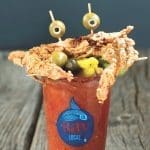 A Bloody Mary in a Bay Local glass topped with a fried soft-shell crab, olives on picks, and pickled vegetables.