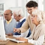 Elder lady with glasses helping her friend with computer issue