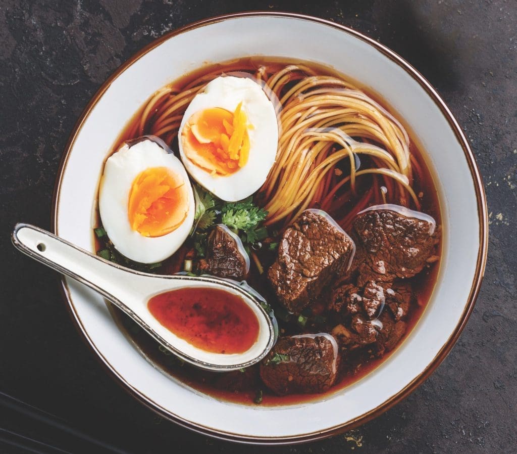 Asian noodles in broth with slow cooked Beef and Egg on dark background