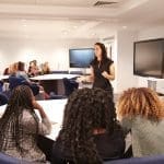 Female teacher addressing university students in a classroom