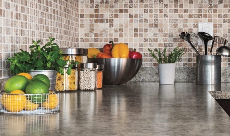 Modern kitchen countertop with food ingredients and green herbs.