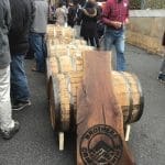 Oak barrels stacked beside a carved wood sign reading "Brothers Craft Brewing," with people gathered outdoors.