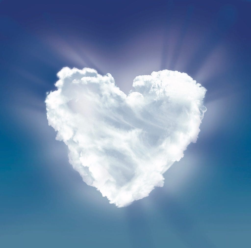A white, fluffy cloud shaped like a heart against a blue sky with sunburst rays.